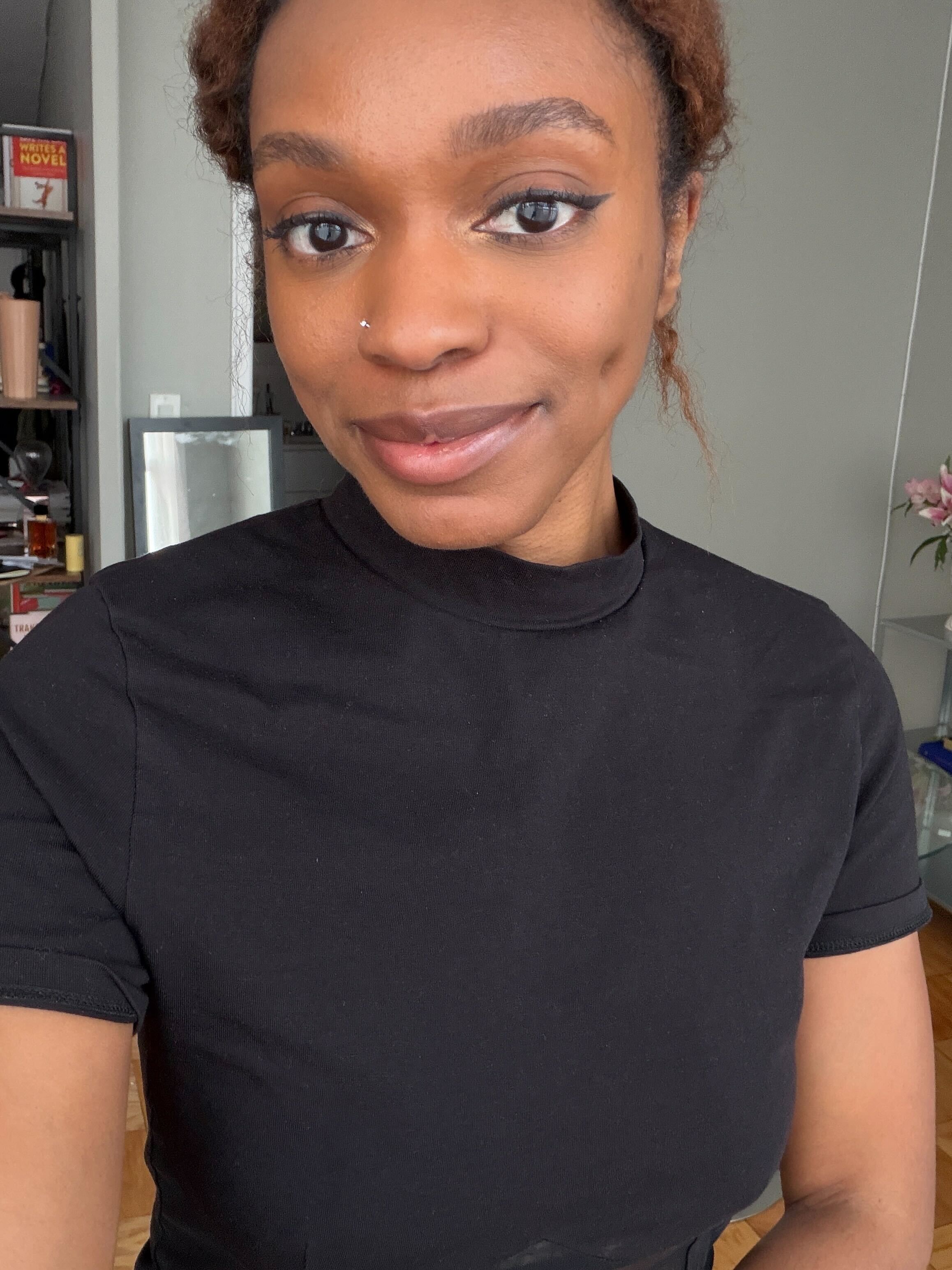 A woman wearing a black turtleneck T-shirt with her hair tied up in a bun
