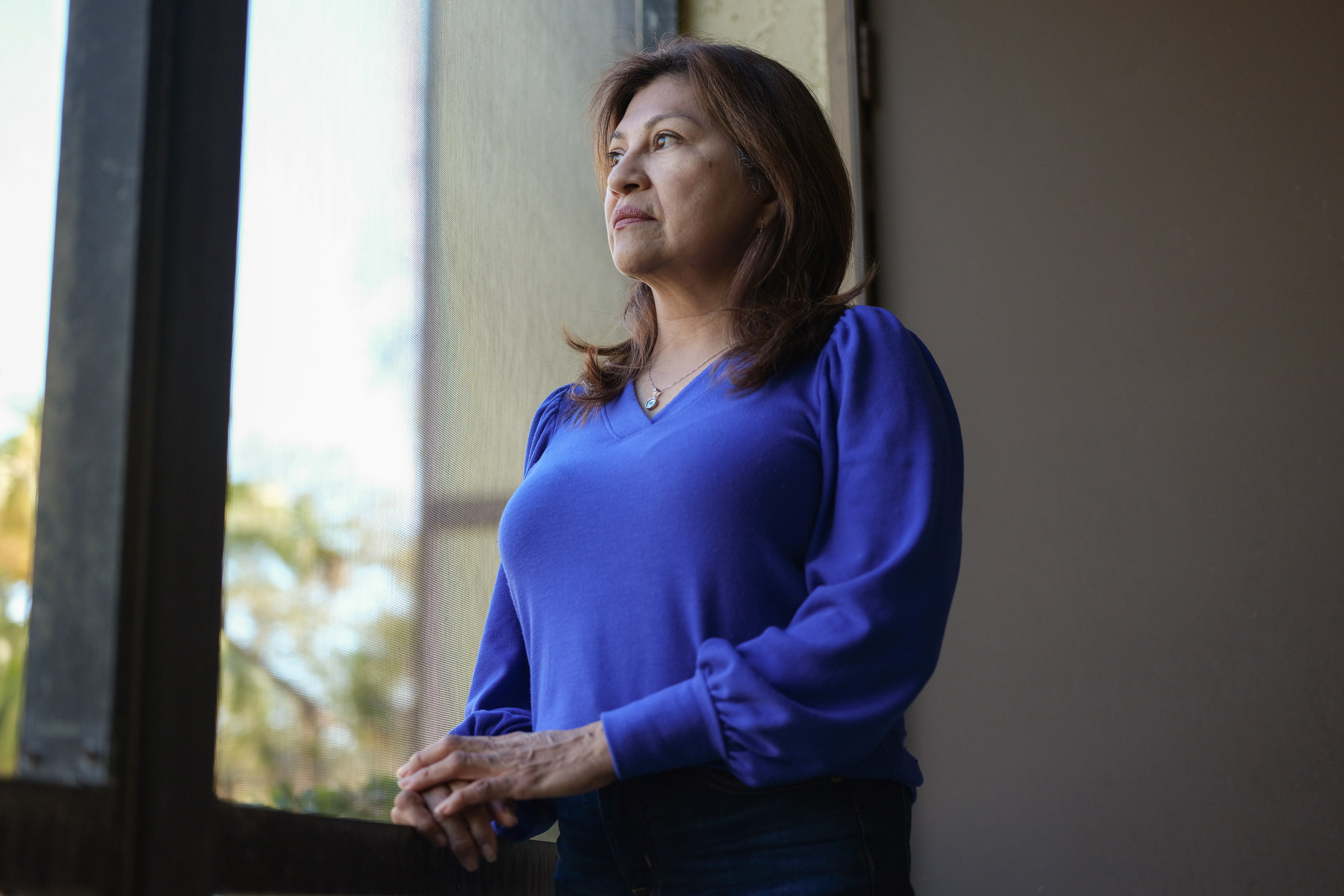 Lorena Alvarado Hill paints portraits indoors. She is looking out the window.