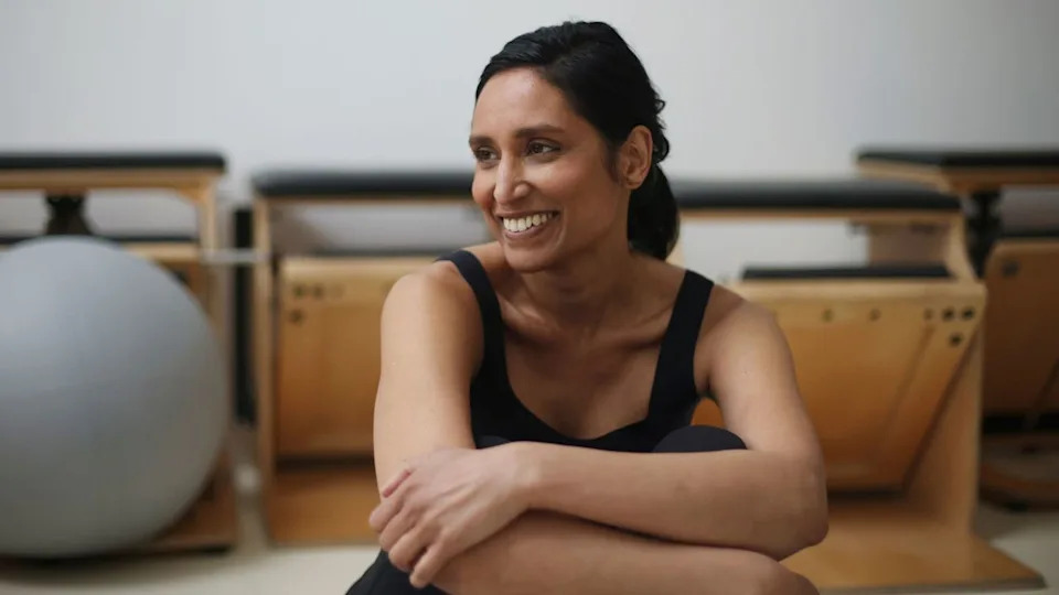 Woman sitting and smiling while doing bodyweight pilates training.
