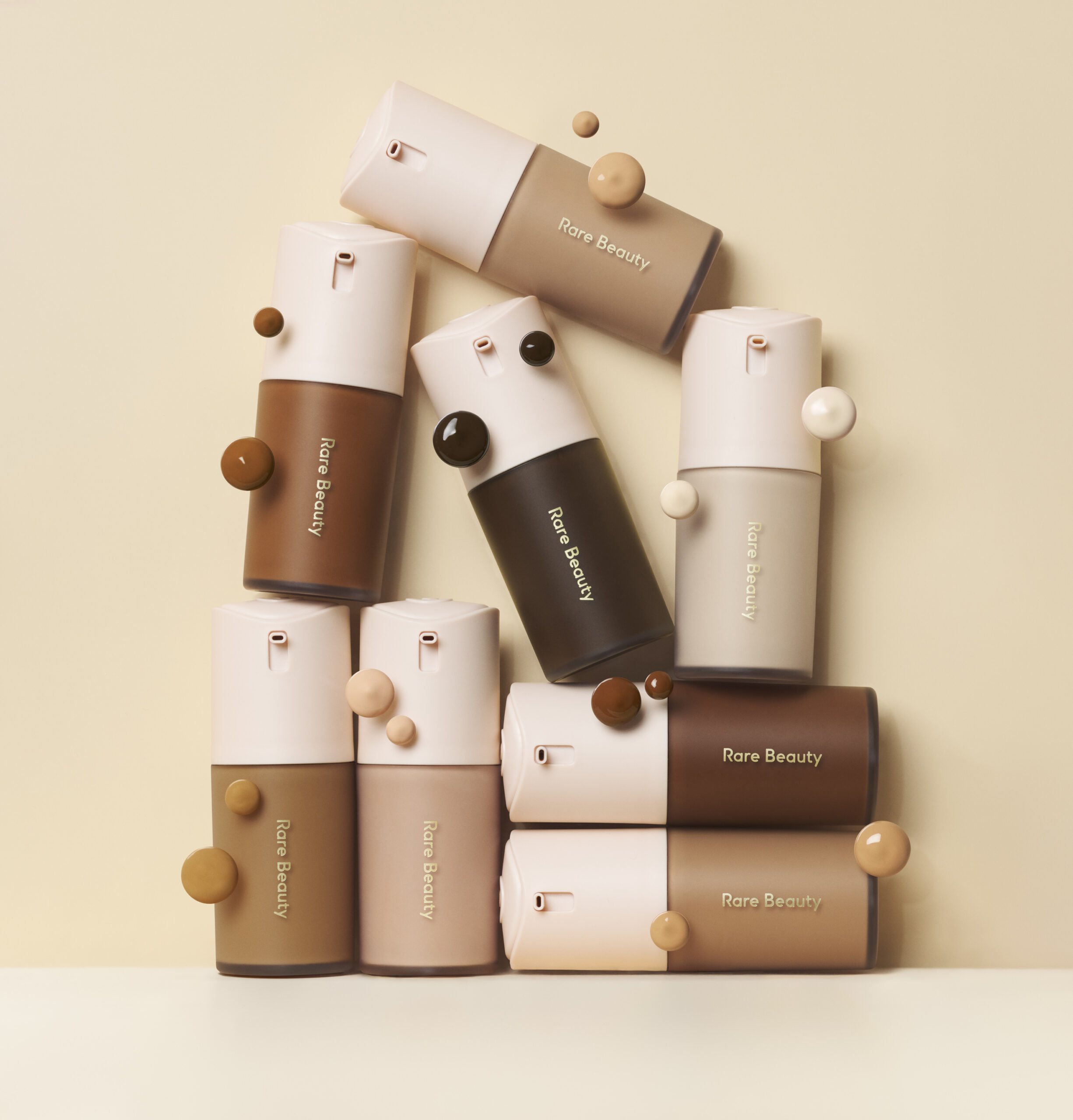 Assortment of foundation bottles with pink tops on cream background