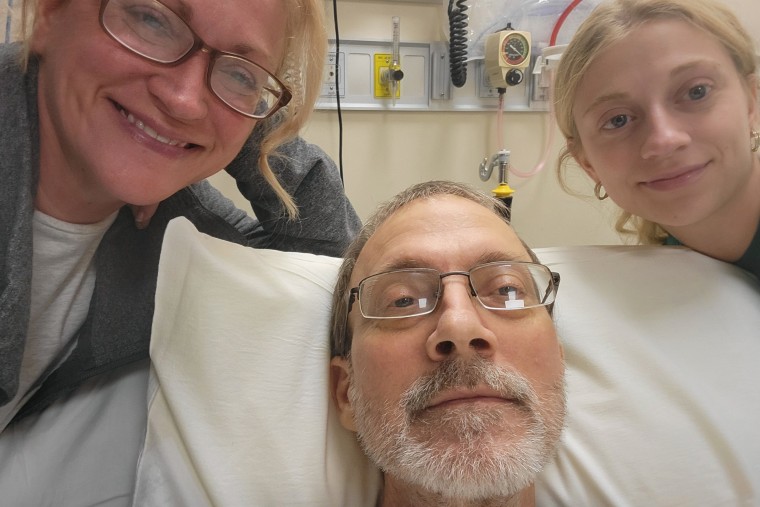 Becky (left) and Amiyah (right) take a selfie with Eric Tennant in his hospital bed.